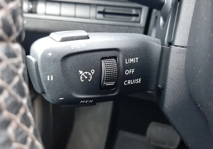 Gros plan sur la commande de régulateur de vitesse du Peugeot 3008 2023, intérieur noir avec molette texturée.