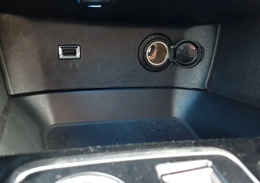 Prise USB et allume-cigare ouverts dans l’espace de rangement central du Peugeot 3008 gris platinium 2023.