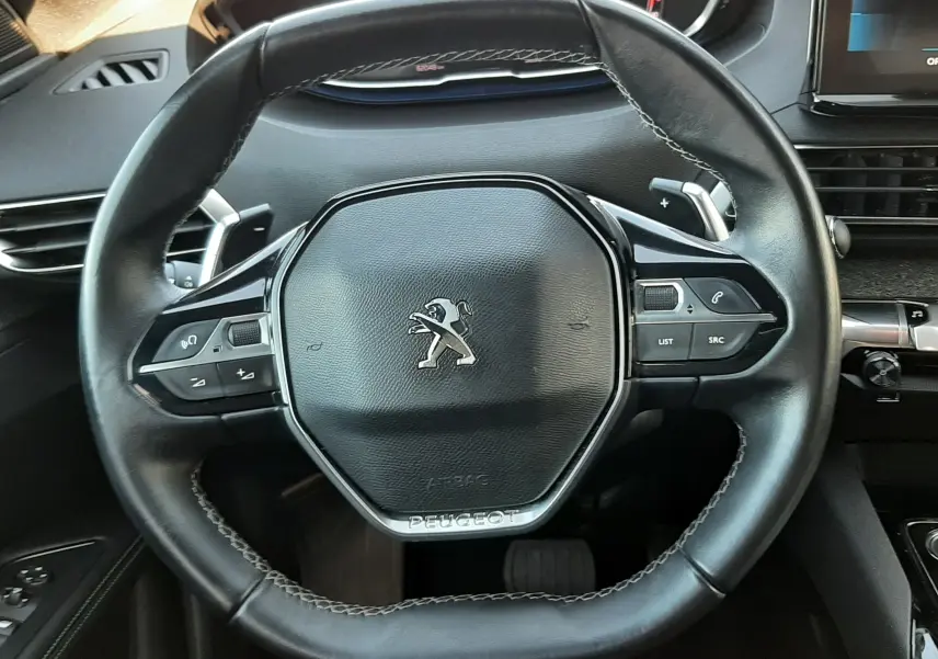 Vue rapprochée du volant cuir noir du Peugeot 3008 2023 avec commandes intégrées et tableau de bord numérique.