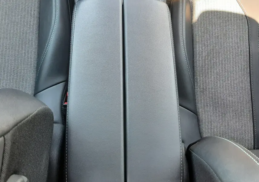 Vue plongeante sur l'accoudoir central en cuir noir et les sièges tissu gris du Peugeot 3008 2023.
