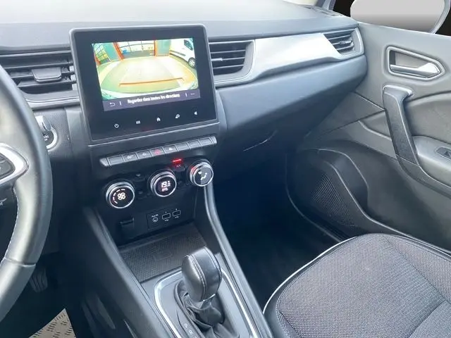 Vue intérieure côté passager du tableau de bord et console centrale du Renault Captur blanc nacré 2021 avec écran tactile et boîte auto.
