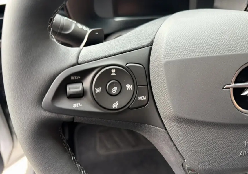 Gros plan sur le volant cuir multifonctions gris de l’Opel Corsa Hybrid 110 E-DCT6 avec commandes de régulateur et chauffage.