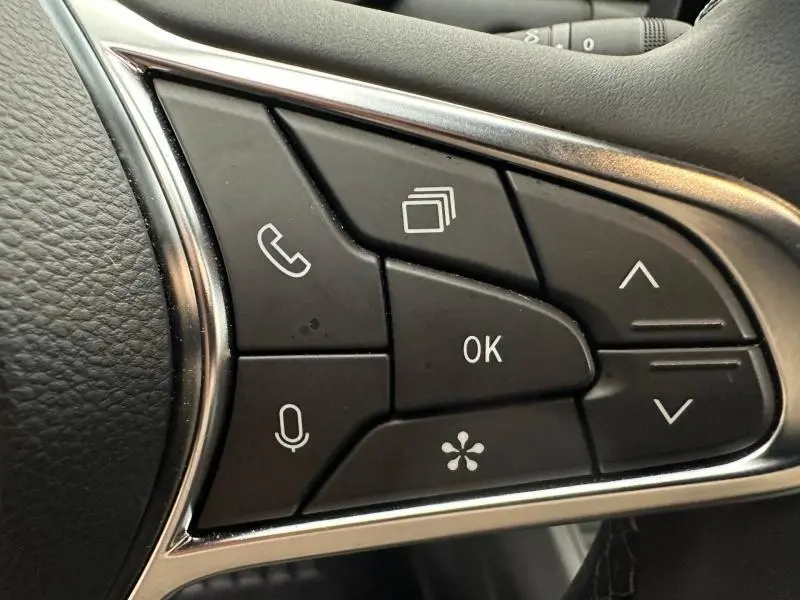 Gros plan sur les commandes au volant du Renault Captur 2025, boutons noirs avec icônes blanches et contour chromé.