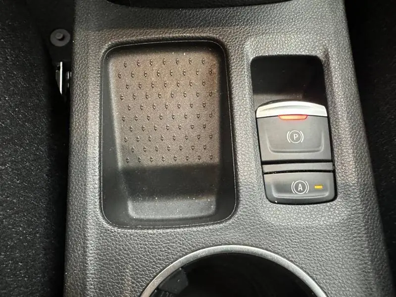 Gros plan sur la console centrale noire du Renault Captur 2025, avec boutons de frein à main électronique et arrêt/démarrage automatique.