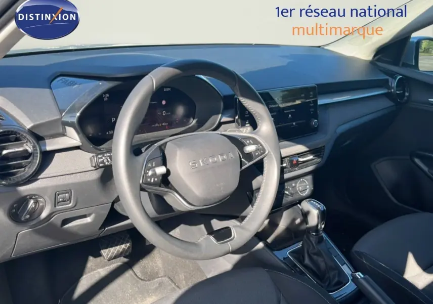 Vue intérieure du poste de conduite d'une Skoda Fabia 2025, tableau de bord et volant en gris noir, avec boîte automatique.