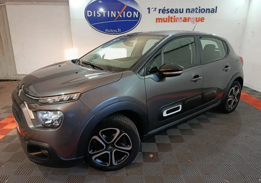 Citroën C3 gris foncé vue 3/4 avant droit, avec protections latérales noires et jantes distinctives.