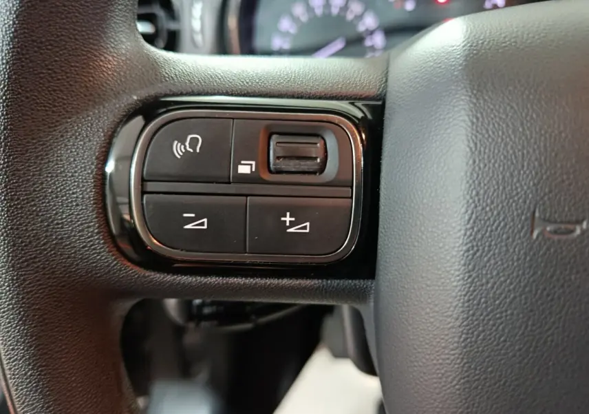 Gros plan sur les commandes de volume et reconnaissance vocale sur le volant noir du Citroën C3 2024.