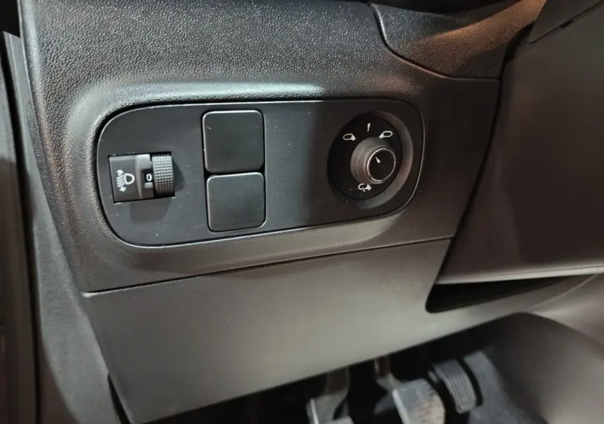 Gros plan sur les commandes de réglage des phares et des rétroviseurs côté conducteur d’une Citroën C3 gris foncé 2024.