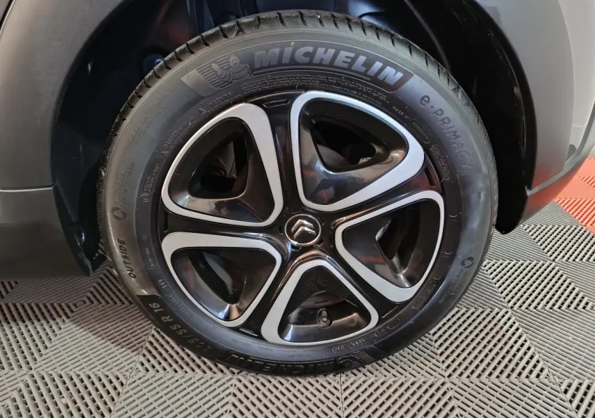 Gros plan sur la roue avant droite d'une Citroën C3 gris foncé, jante alliage noire et argent avec logo Citroën central.