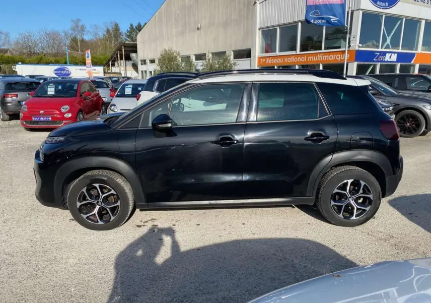 Profil côté gauche d'un Citroën C3 Aircross noir 2023 avec jantes alliage diamantées sur un parking extérieur.