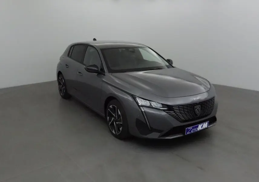 Peugeot 308 gris Sellenium vue 3/4 avant droit, avec calandre noire et jantes alliage distinctives.