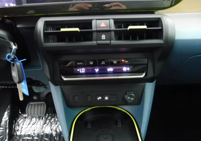 Vue rapprochée du tableau de bord bleu et noir de la Fiat Grande Panda 2025 avec commandes climatisation et prise 12V.