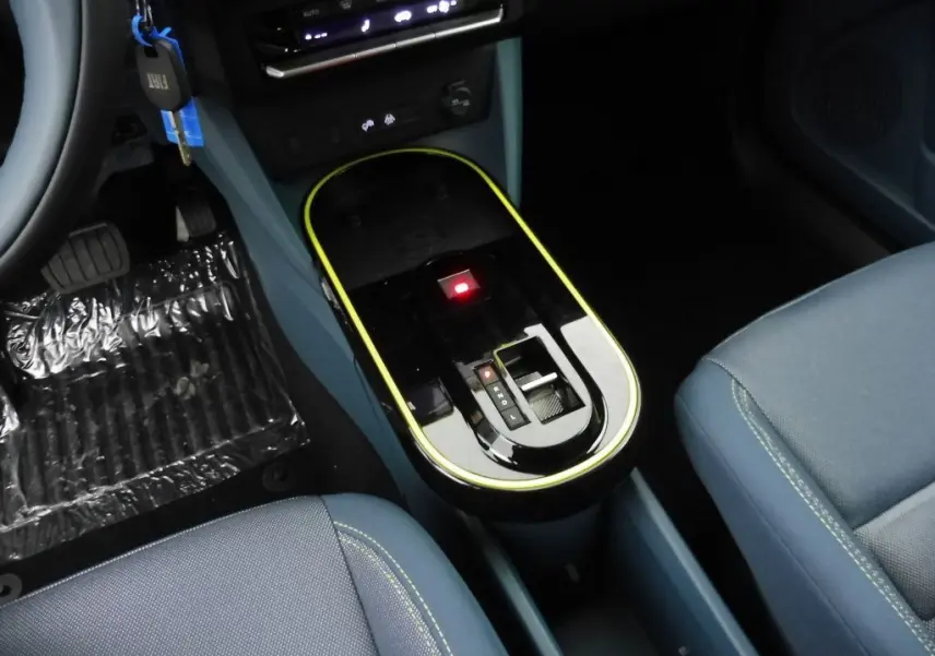 Gros plan sur la console centrale noire avec liseré jaune de la FIAT Grande Panda 2025, sièges tissu bleu visible.