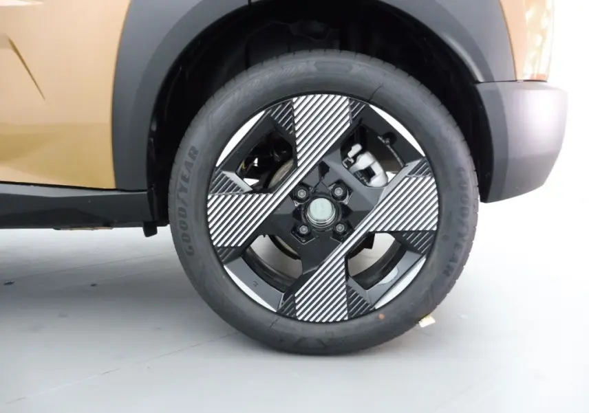 Gros plan sur la roue avant gauche de la Fiat Grande Panda 2025 en bronze luna, avec jante noire et motifs diagonaux blancs.