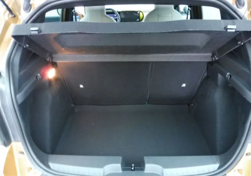 Coffre ouvert vu de l'arrière d'une FIAT Grande Panda 2025 bronze Luna, montrant un espace de chargement vide et éclairé.