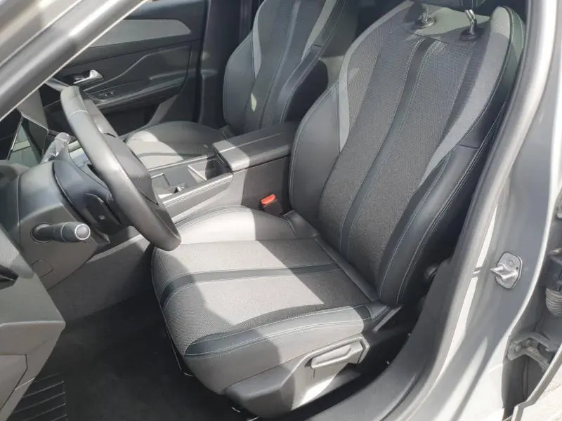 Vue intérieure côté conducteur de la Peugeot 308 2024 gris Sélénium, sièges tissu et cuir avec accoudoir central