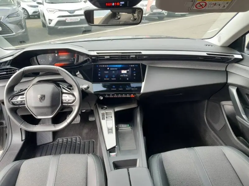 Vue intérieure avant de la Peugeot 308 2024 avec tableau de bord moderne et écran tactile central noir brillant.