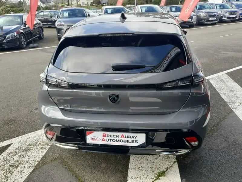 Vue arrière d'une Peugeot 308 gris Sélénium 2024 avec feux arrière LED et lunette arrière surteintée.