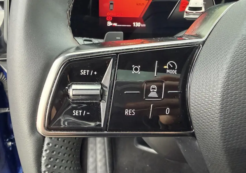 Gros plan sur les commandes de régulateur de vitesse au volant du Renault Austral bleu Iron, intérieur noir.