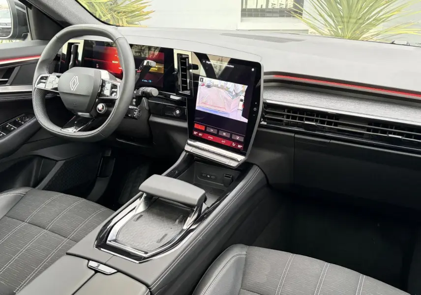 Vue intérieure côté conducteur du Renault Austral E-Tech 2025, tableau de bord noir avec écran tactile central vertical et volant compact.