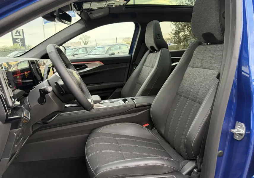 Vue intérieure côté conducteur du Renault Austral bleu, montrant les sièges gris et le volant textile enduit.