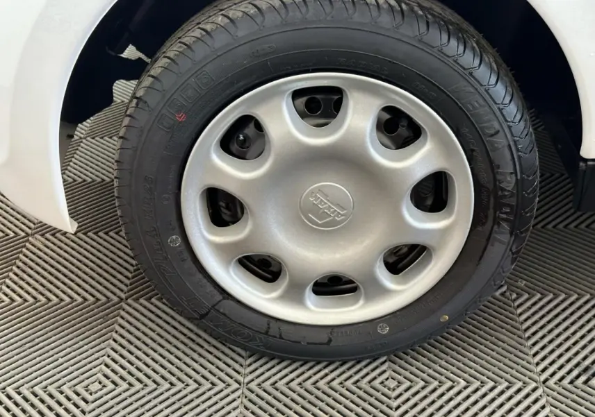 Gros plan sur la roue avant droite d'une Aixam Minauto E Access blanche, montrant le pneu et l'aile du véhicule.