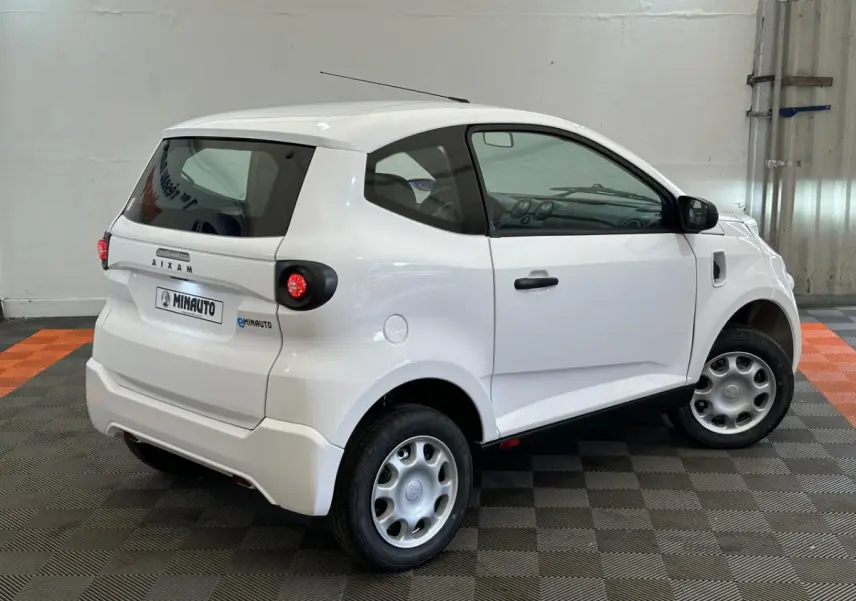 Vue 3/4 arrière droite d'une Aixam Minauto E Access blanche avec rétroviseur caméra côté conducteur.