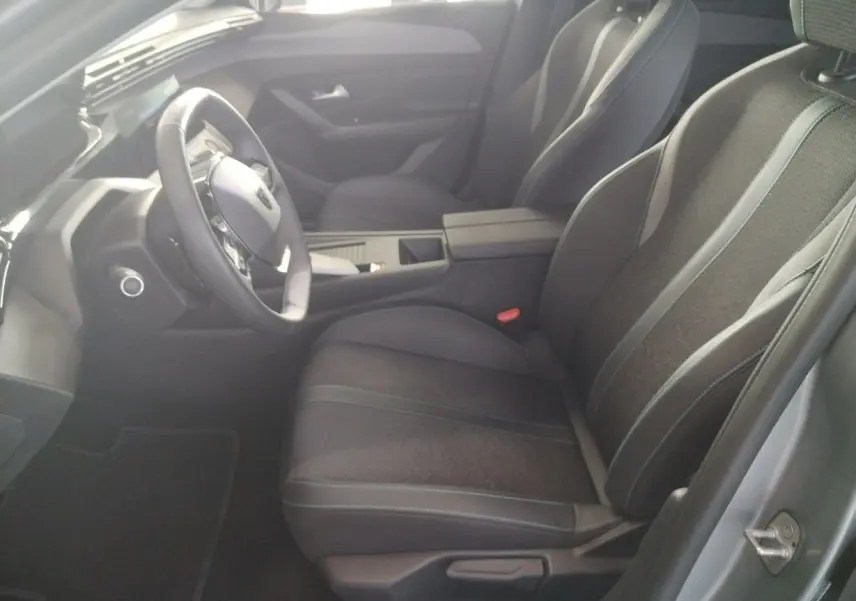 Vue intérieure côté conducteur de la Peugeot 308 SW Hybrid 145 e-DCS6 Allure 2025, sièges noirs et tableau de bord moderne.