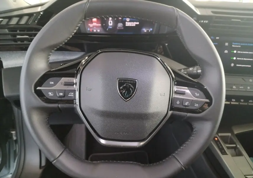 Gros plan sur le volant cuir noir du Peugeot 308 SW Hybrid 145 e-DCS6 Allure avec logo lion et commandes intégrées.