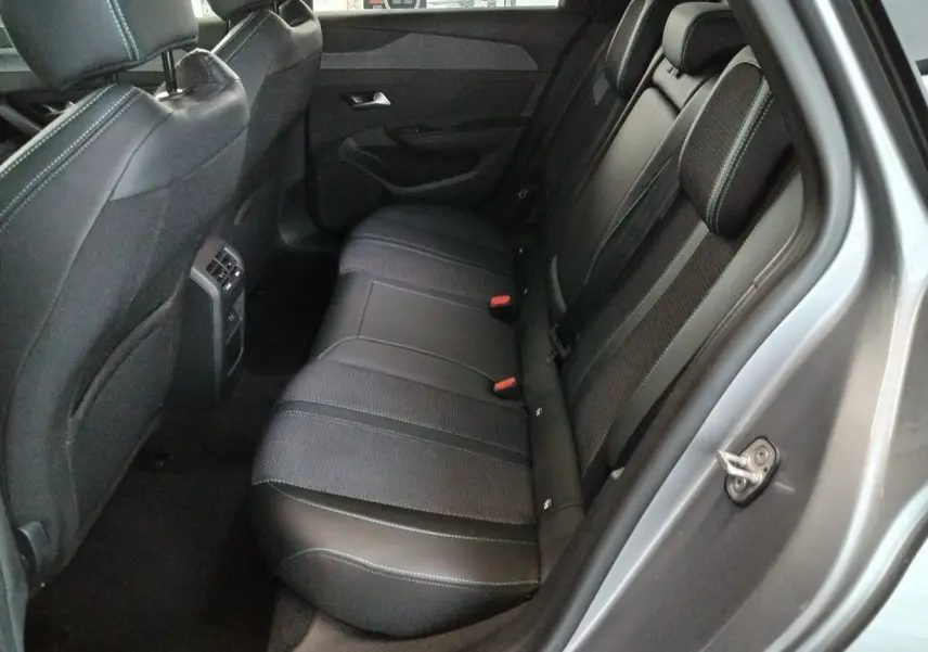 Vue côté droit de l'habitacle arrière du Peugeot 308 SW Hybrid 145 gris Artense, sièges en cuir et tissu noir avec surpiqûres.