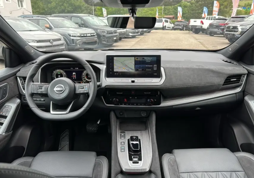 Vue intérieure avant du Nissan Qashqai E-POWER 205 Tekna Plus, volant cuir multifonctions et écran tactile central.