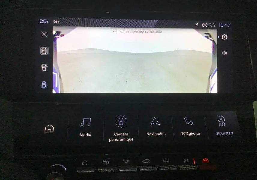 Écran intérieur montrant la vue de la caméra 360 du Peugeot 308 blanc Okenite avec interface tactile et commandes.