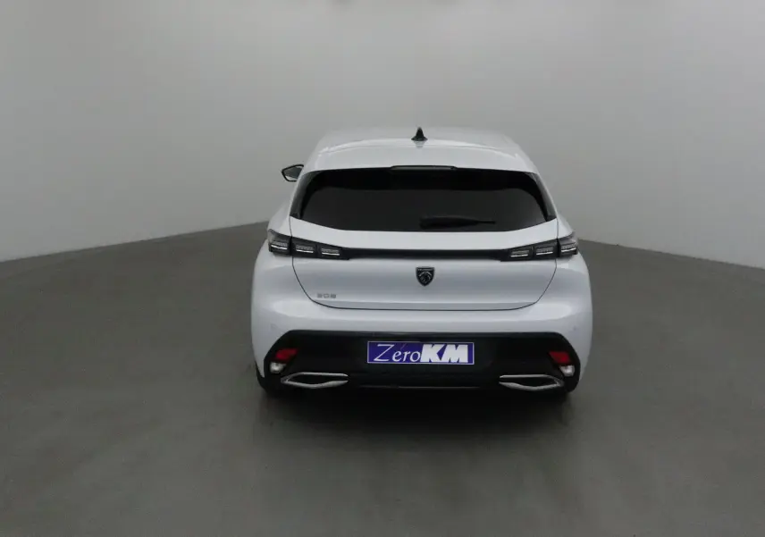 Vue arrière d'une Peugeot 308 blanche Okenite 2025 avec feux LED et double sortie d'échappement chromée.