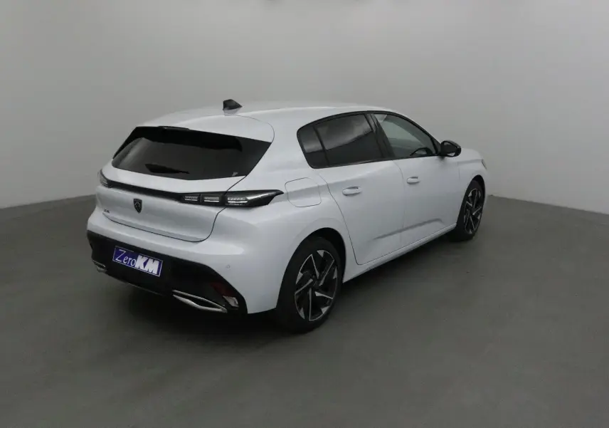 Peugeot 308 blanc Okenite vue 3/4 arrière droit, avec jantes alliage noires et vitres teintées.