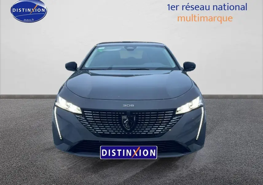 Vue frontale d'une Peugeot 308 gris sélénite 2025 avec phares LED allumés et calandre distinctive.
