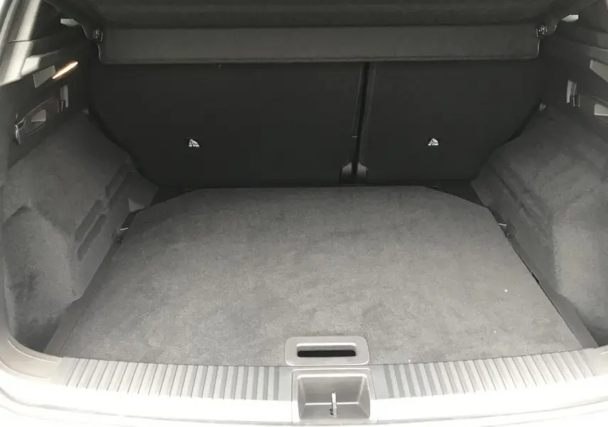 Coffre ouvert vu de l'arrière d'un Renault Austral blanc, avec plancher plat et habillage intérieur gris foncé.