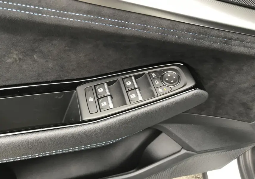 Détail de la porte côté gauche du Renault Austral blanc, avec commandes des vitres et surpiqûres bleues visibles.