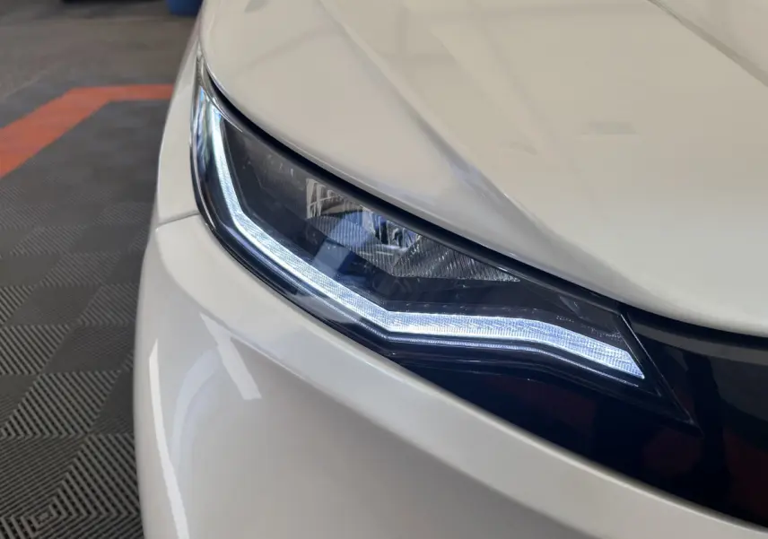 Gros plan sur le phare avant droit blanc d'une Aixam Ambition E City Pack 2026 avec éclairage LED distinctif.