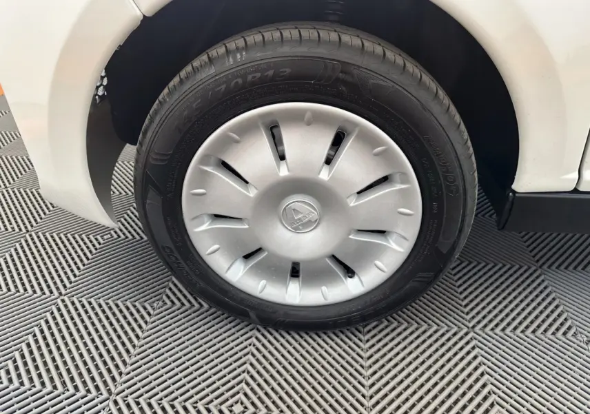 Gros plan sur la roue avant gauche blanche d'une Aixam Ambition E City Pack 2026 avec enjoliveur argenté et logo central.