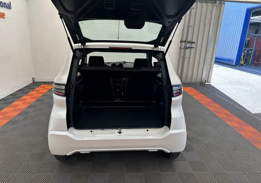 Vue arrière d'une Aixam Ambition E City Pack blanche 2026 avec coffre ouvert et intérieur sombre visible.