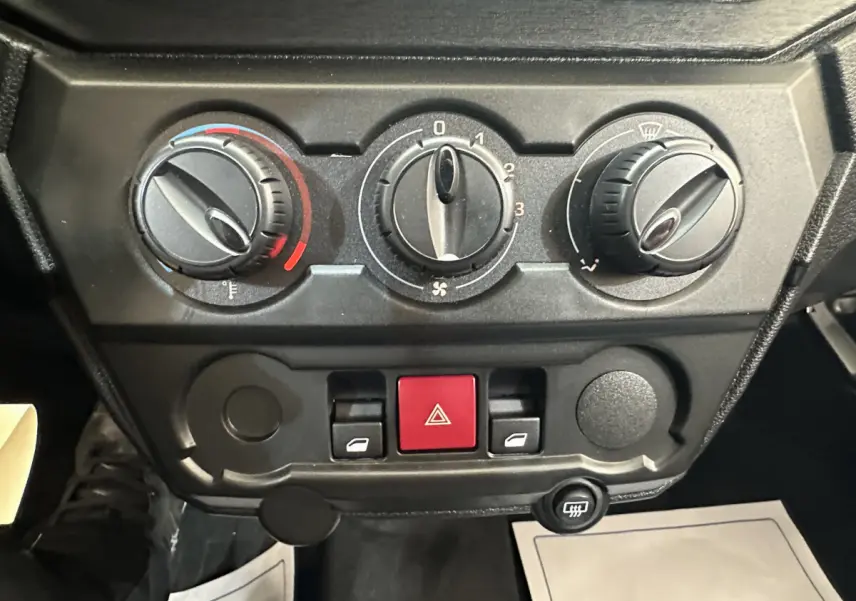 Vue rapprochée des commandes de climatisation et des boutons de sécurité du tableau de bord de l'AIXAM AMBITION E CITY PACK 2026.