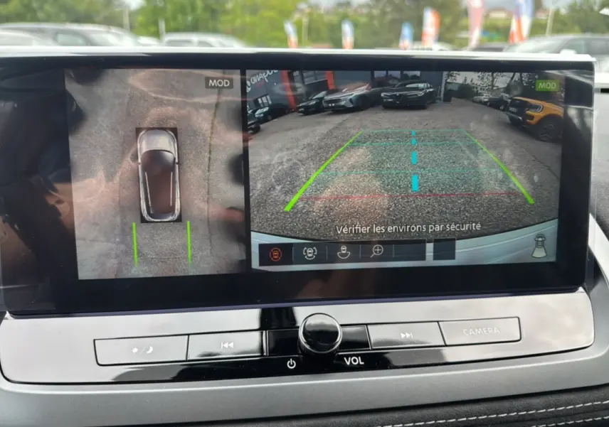 Écran de caméra 360° du Nissan Qashqai blanc lunaire avec toit noir, affichant vue arrière et vue aérienne du véhicule.