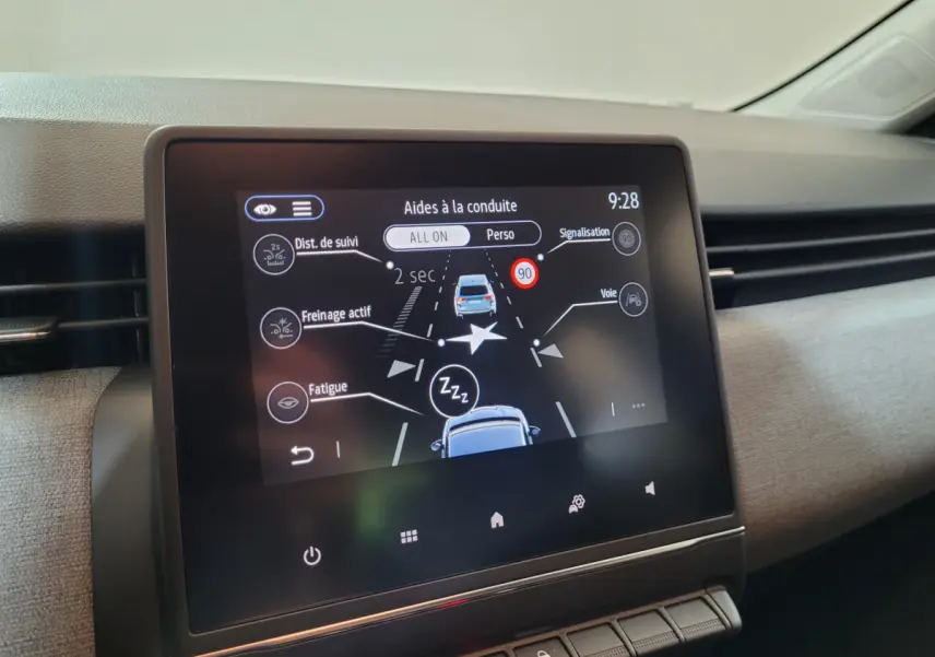 Écran tactile central affichant les aides à la conduite dans l’habitacle d’une Renault Clio gris foncé, vue de face.