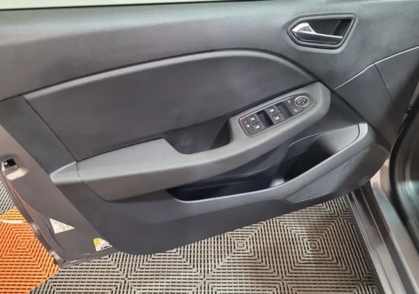 Vue intérieure côté gauche de la porte avant d'une Renault Clio gris foncé avec commandes électriques des vitres et poignée intégrée.