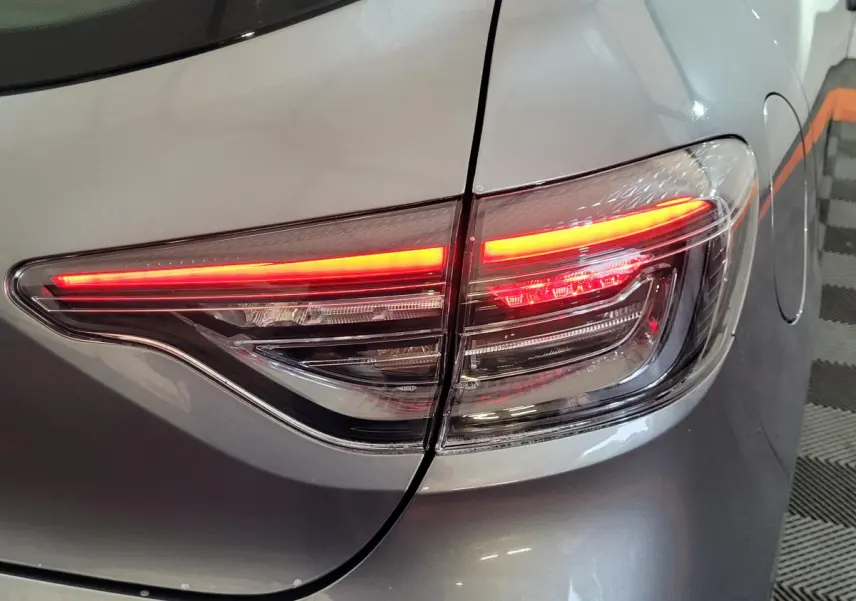 Feu arrière droit allumé d'une Renault Clio gris foncé Evolution Blue dCi 100, vue rapprochée sur le coffre et la trappe à carburant.