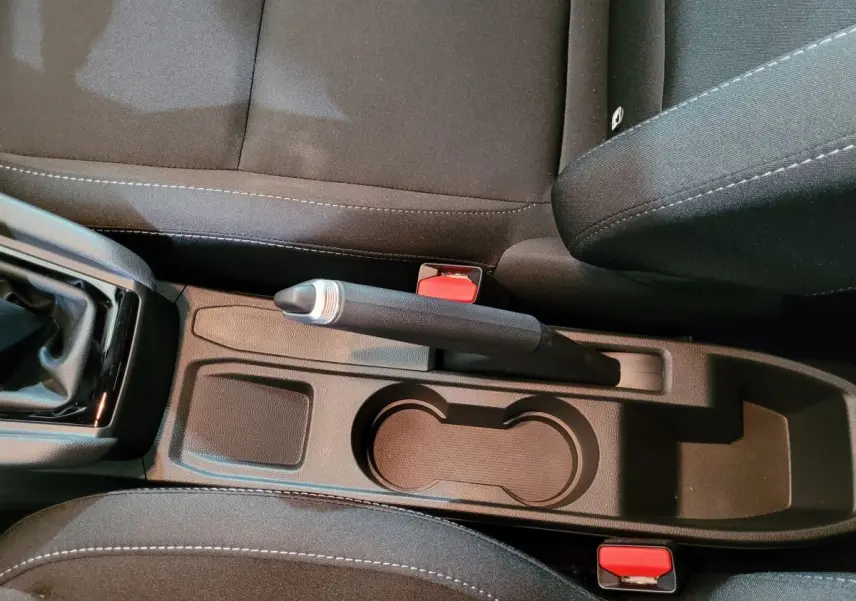 Vue rapprochée de la console centrale noire de la Renault Clio gris foncé, avec frein à main et porte-gobelets visibles.