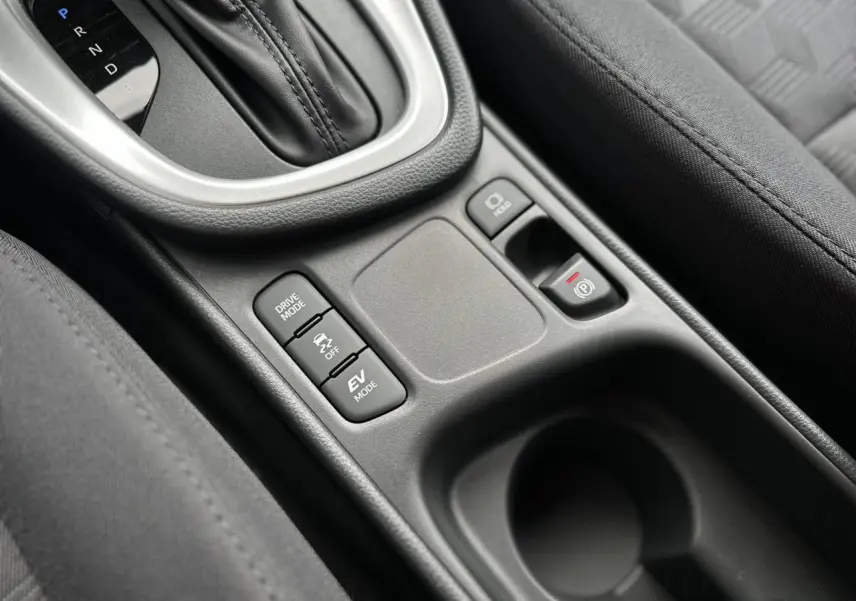 Gros plan sur la console centrale noire de la Toyota Yaris Hybride 2025 avec levier de boîte auto et boutons de modes de conduite.