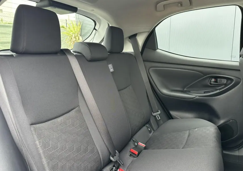 Vue intérieure arrière droite des sièges arrière en tissu noir de la Toyota Yaris Hybride 2025, avec ceinture de sécurité visible.