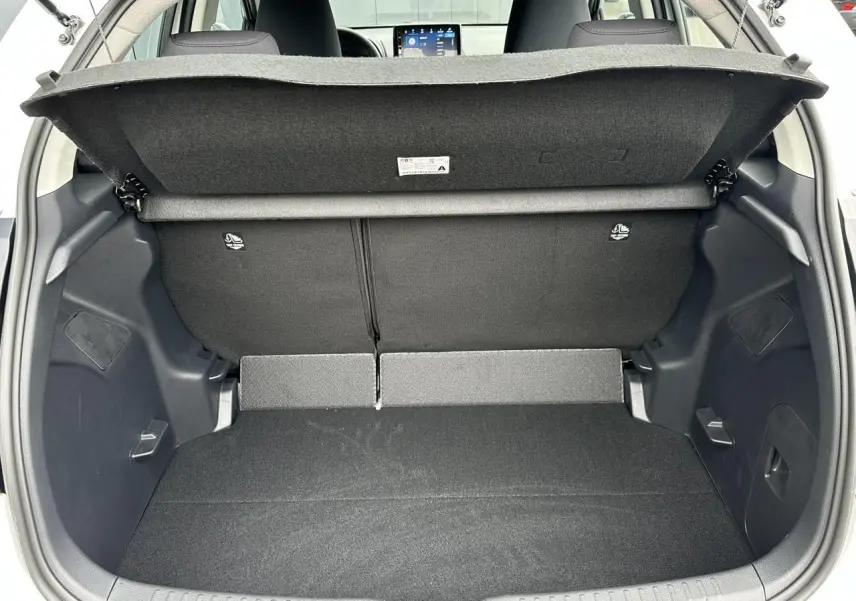 Coffre ouvert vu de l'arrière d'une Toyota Yaris blanche, montrant le double plancher et la banquette arrière noire.
