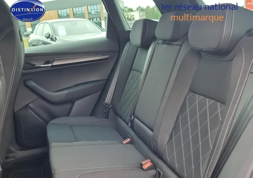 Vue latérale droite de l'intérieur arrière noir du Skoda Karoq 1.5 TSI 150 Sportline avec sièges en tissu matelassé.